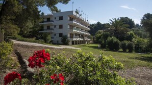 A multi-story building with balconies, surrounded by greenery and trees. - Daniil's Seafront Apartment  (Νικήτη)