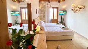 A hotel room with two beds, wooden ceiling beams, stone wall, and a TV on the wall. - Eros villa ,private Pool,short drive to beach (Rethymno)
