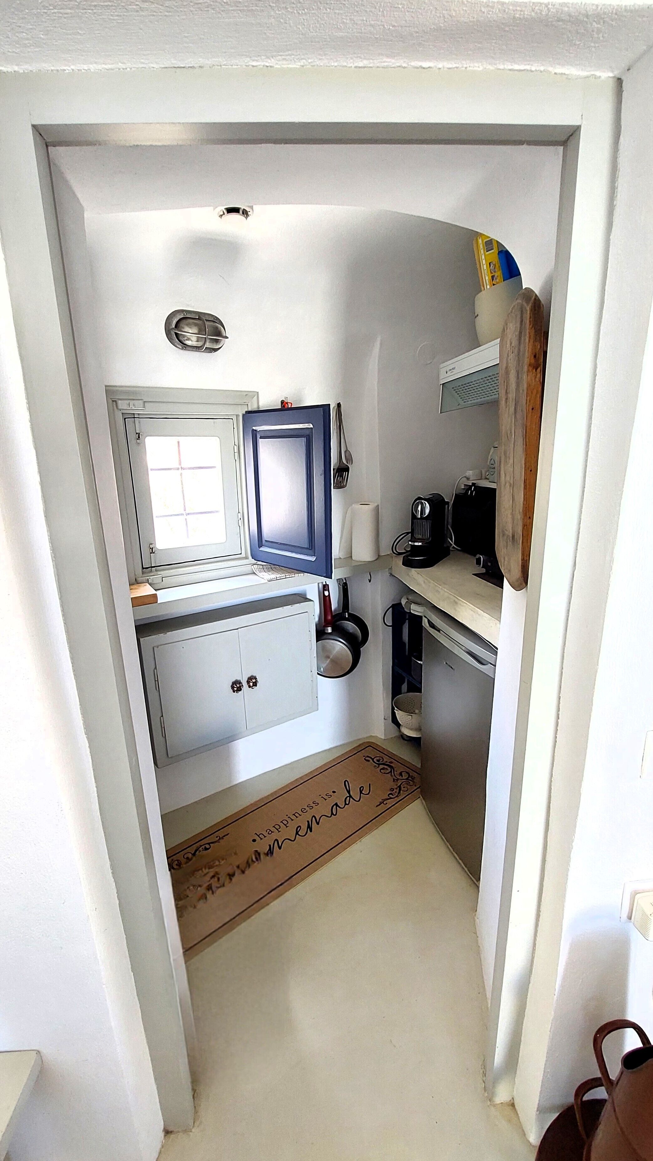 A narrow kitchen with a window, a blue cabinet, and a wooden door.