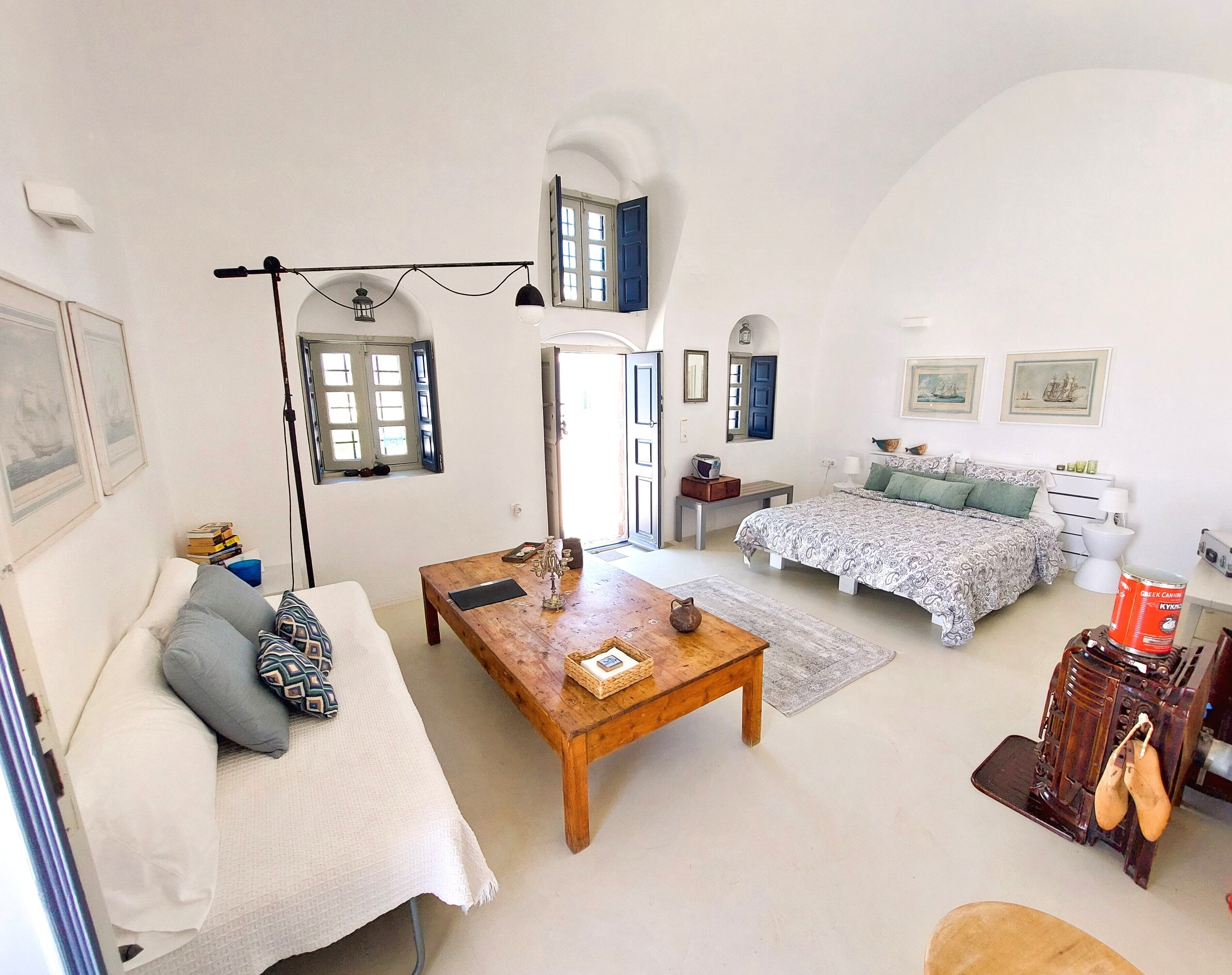 A spacious living area with a sofa, coffee table, and a bed with a patterned bedspread.