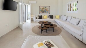 Un salon moderne avec un téléviseur à écran plat, un ensemble de canapés, une table basse et un livre posé sur une table.