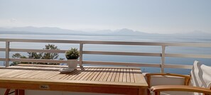 Un balcón con una mesa de madera, una planta en maceta y una silla blanca.