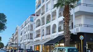 A multi-story hotel with balconies, a palm tree in front, and cars parked along the street. - Two bedroom apartment only 500 meters to the beach (Ιαλυσός)