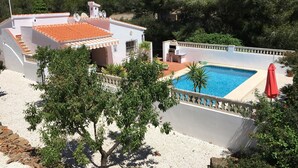 A pool area with a white building, a red umbrella, and a view of a mountainous landscape. - Private Villa With Pool Near Golf Course Short Drive to Beach (Unknown)
