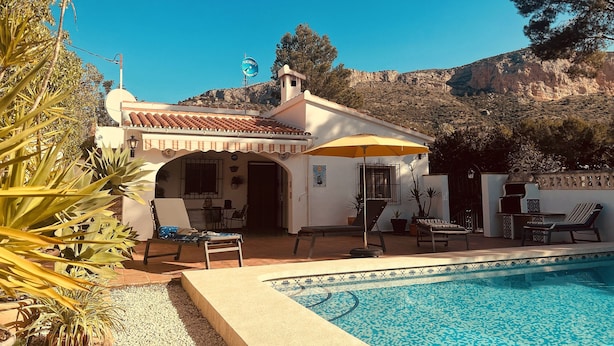 A poolside area with lounge chairs, a covered seating area, and a view of a mountainous landscape. - Private Villa With Pool Near Golf Course Short Drive to Beach (Unknown)