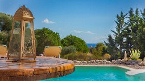 Ein Poolbereich mit Holzterrasse, Laterne und Stuhl.