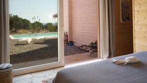 Ein Zimmer mit Bett, Blick auf einen Pool und einer Holzwand.