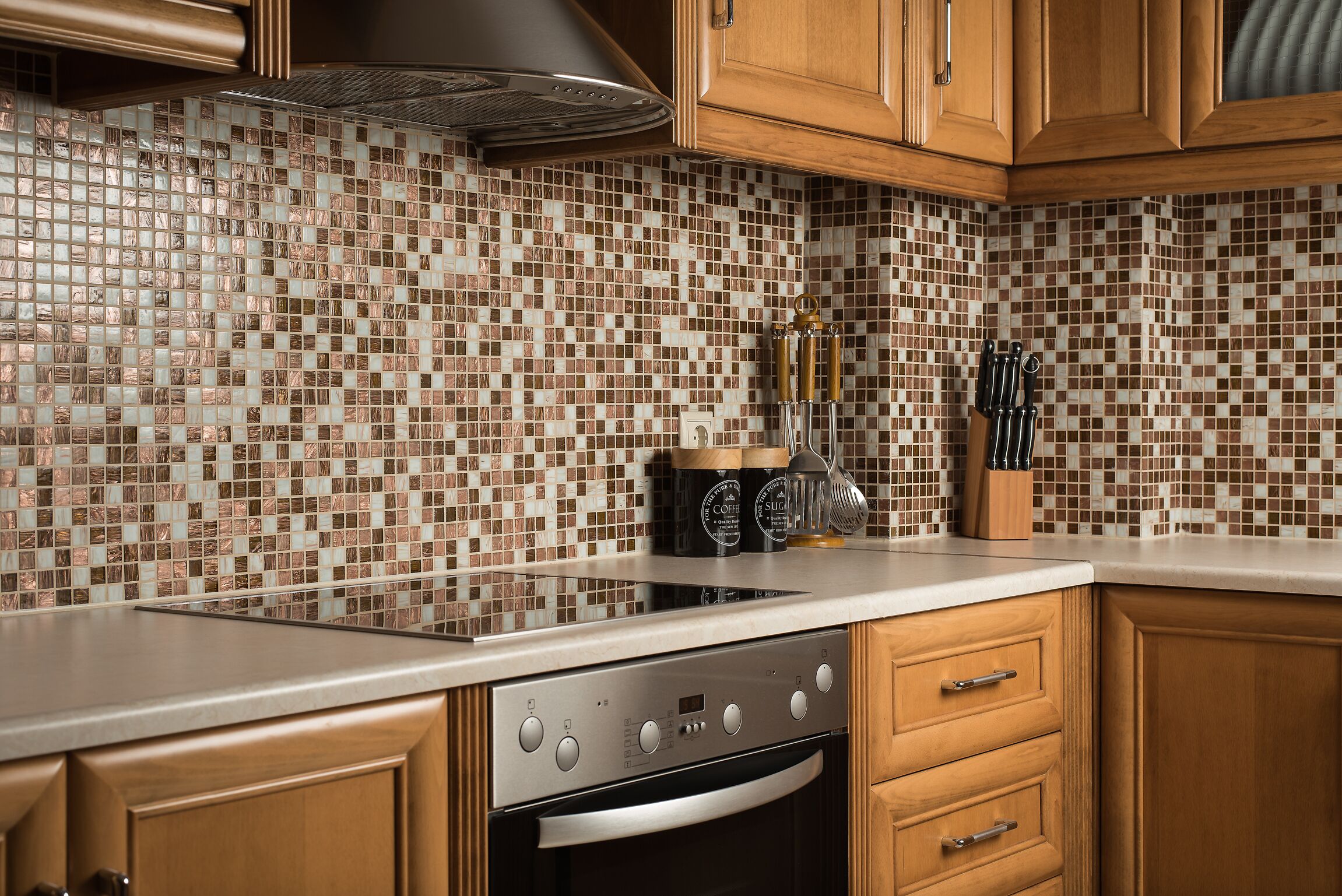 A kitchen with wooden cabinets, a stainless steel stove, and a tiled backsplash.