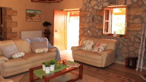 Una sala de estar acogedora con dos sofás beige, una mesa de centro de madera y una pared de piedra.