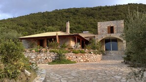 Una casa de piedra con techo de tejas, un sendero de piedra y un paisaje montañoso al fondo.