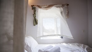 A bed with white linens, a pair of rolled towels, and sheer curtains. - Arch Villa traditional holiday house on Rhodes (Σορωνή)