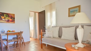 Ein Wohnzimmer mit einer Couch, einem Tisch mit Lampe und einem Gemälde an der Wand.
