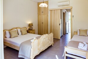 Ein Hotelzimmer mit einem großen Bett, einem kleineren Bett, einem Kleiderschrank, einem Nachttisch mit Lampe und einem durchgehenden Türspalt sichtbaren Badezimmer.
