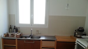 Una cocina compacta con un lavamanos, armarios de madera, una ventana y un microondas.