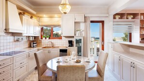 A modern kitchen with white cabinets, a dining table with chairs, and a chandelier. - Villa Vanelia Mare - Guest Favorite Elegant Stay! Authentic Greek Hospitality! (Χανιά)