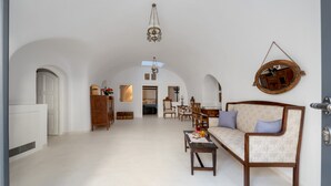 Ein geräumiges Wohnzimmer mit hoher Decke, einem Kronleuchter, einer Couch, einem Couchtisch und einem Essbereich mit Stühlen und Tisch.