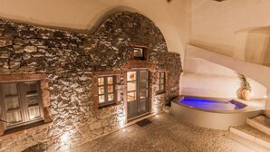 Ein Innenraum mit Steinwänden und Steinboden, ein kleiner Pool und eine Treppe.