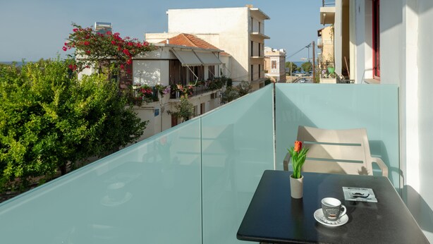 A balcony with a table, a chair, a potted plant, and a cup. - Apartment very close to the water and the beach (Χανιά)