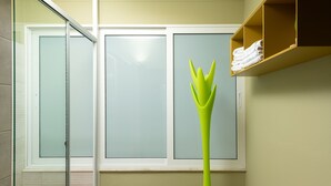 A bathroom with a glass shower enclosure, a green vase, and a towel shelf. - Apartment very close to the water and the beach (Χανιά)