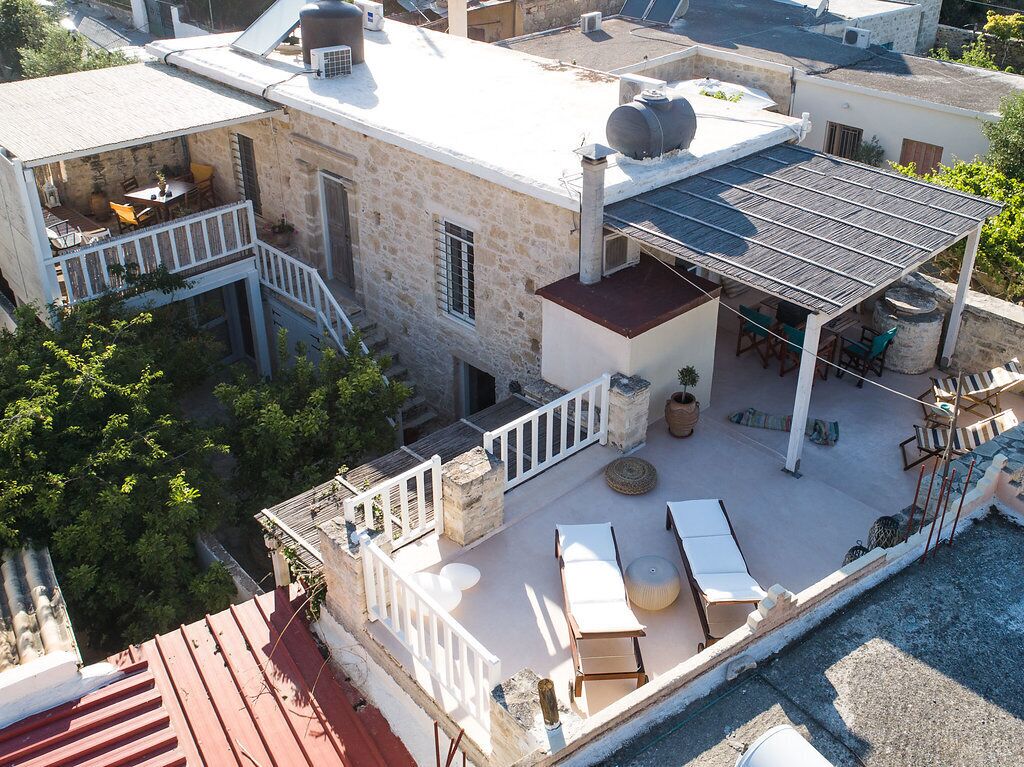 Una terraza en la azotea con mobiliario exterior, un depósito de agua y una pérgola.