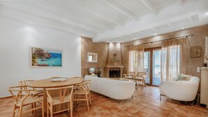 Amplia sala de estar con una mesa de comedor de madera, sofá blanco y chimenea.