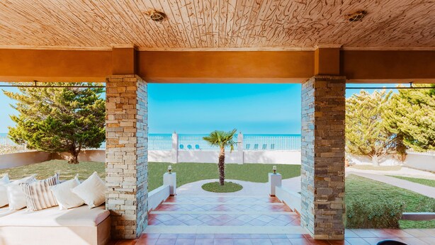 Un patio al aire libre con un muro de piedra, vista de un edificio y una palmera.