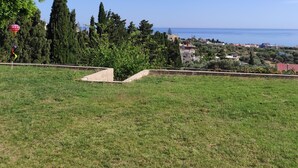Une zone herbeuse offrant une vue dégagée sur une ville côtière et sur la mer en arrière-plan.