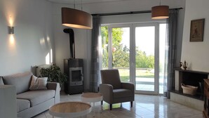 Un salon moderne comprenant un canapé, un fauteuil et une table basse, une cheminée et une grande porte-fenêtre coulissante donnant sur l’extérieur.