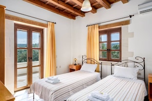 A bedroom with two beds, wooden ceiling beams, large windows with curtains, and a view of greenery outside. - Wedding Villa w/Pool, BBQ, Ping Pong, 23 people (Πικρής)