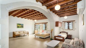 Un vaste espace de vie doté d’un haut plafond en bois, d’un canapé, d’un lit, d’un banc et d’un divan à motifs floraux.