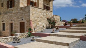 Un bâtiment en pierre doté d’une cour intérieure agrémentée d’escaliers et de plantes en pot.