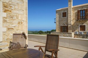 Un edificio in pietra con un balcone, sedie di legno e un tavolo.