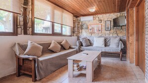 Una sala de estar acogedora con chimenea de piedra, techo de madera y dos sofás con cojines.