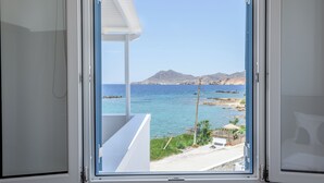 Janela com vista para uma paisagem costeira, incluindo uma praia, uma montanha e o mar.