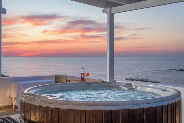 A wooden hot tub on a balcony with a sunset view over the ocean. - Luxurious oceanfront villa with unique sunset & hot tub (Πολλώνια)