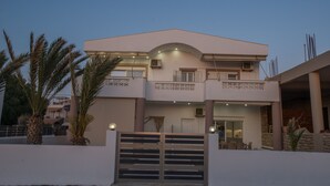 Een modern herenhuis met twee verdiepingen, een hekpoort, een balkon en een overdekt terras.