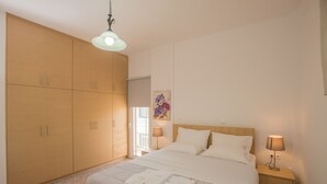 Een slaapkamer met een bed, nachtkastjes, een kledingkast en een hanglamp.
