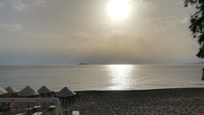 Een strand met zonneschermen en ligbedden.