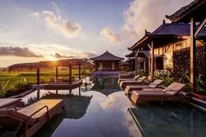 Ein Poolbereich mit Liegestühlen, einer Laube und traditioneller Architektur.