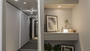A modern hallway with a wooden accent wall, a framed artwork, and a small shelf with decorative items. - Peng Apartment (Taipei)