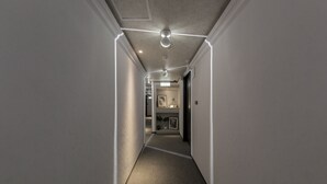 A narrow hallway with a carpeted floor and recessed lighting. - Peng Apartment (Taipei)