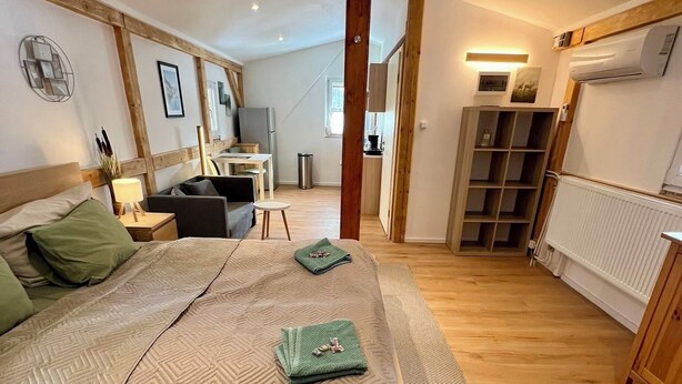 Ein geräumiges Schlafzimmer mit einem großen Bett, einem Schreibtisch und einer kleinen Küche im Hintergrund.