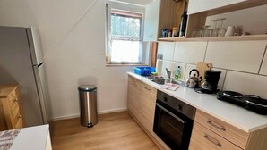 Eine kleine Küche mit Backofen, Spüle und Fenster.