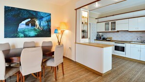 A modern kitchen with white cabinets, a wooden countertop, and a dining area with a table and chairs.