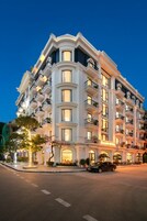 Un hotel de varios pisos con balcones, ventanas amplias y una entrada bien iluminada.