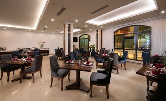 Uma sala de jantar bem iluminada, com várias mesas e cadeiras, janelas amplas com vista para o exterior e um design de teto moderno.