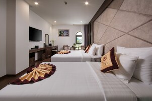 Habitación de hotel con dos camas, televisión, escritorio y ventana con vistas.