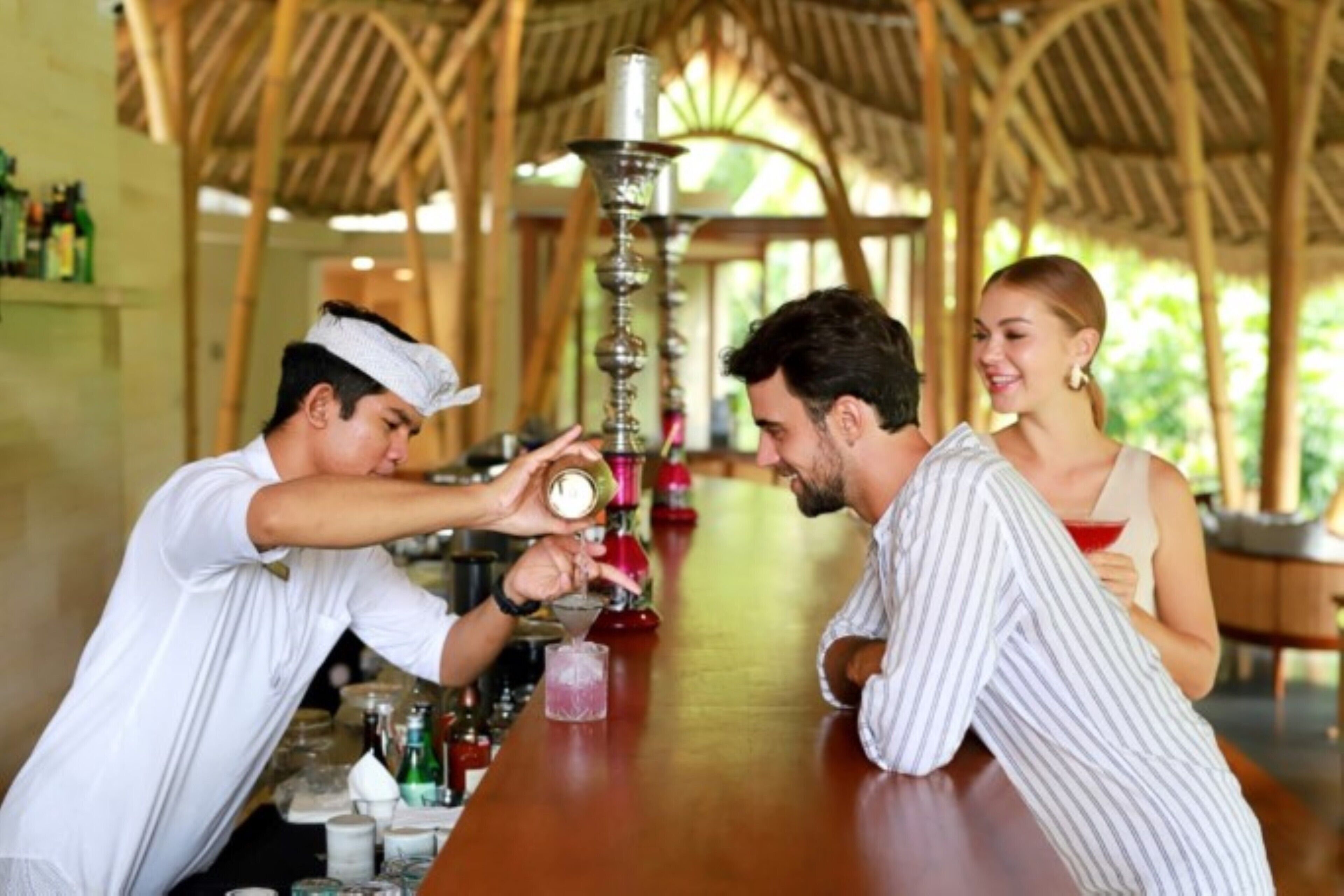 A bar area with a wooden ceiling and a bartender preparing a drink.