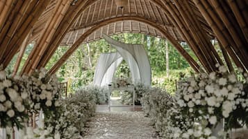 An arched bamboo structure with a white table and floral decorations.
