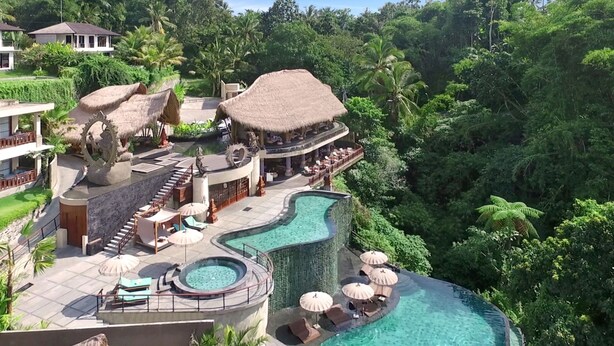 A resort with a pool, lounge areas, and thatched-roof structures.